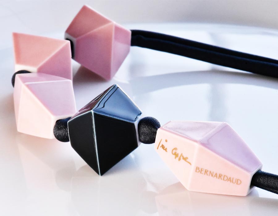 Gros plan sur Be Bold Over avec les perles en porcelaine rose et noire d'un collier créé par l'icône du style Iris Appel pour Bernardaud